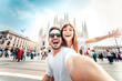 © Davide Angelini - Happy couple taking selfie in front of Duomo cathedral in Milan, Lombardia - Two tourists having fun on romantic summer vacation in Italy - Holidays and traveling lifestyle concept