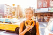 © Maridav - New York people lifestyle photo. Woman eating pretzel in Manhattan, a classic New York City snack. Multiracial asian young professional portrait smiling at camera