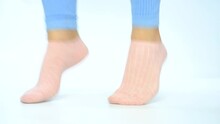 Female Legs In Pink Socks Jumping On White Background Close-up.