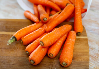 Wall Mural - Bunch of carrots on cutting board. Chopping vegetables, preparing food.