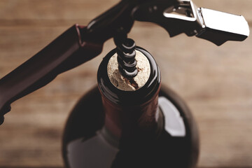 Wall Mural - Opening wine bottle with corkscrew on blurred background, closeup