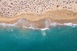 imagen cenital desde dron de una playa color turquesa con mucha gente disfrutando de las olas y la arena