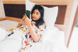 © Reezky - Serious concentrated young woman working from the bed. Hold the smartphone typing.