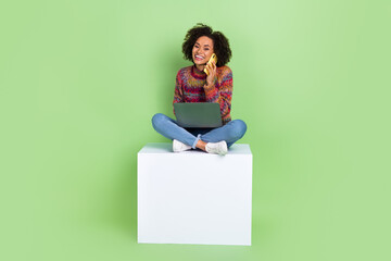 Sticker - Full size portrait of pretty cheerful girl sit podium speak telephone use netbook isolated on green color background