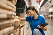 © Chanakon - Young female worker in blue uniform checklist manage parcel box product in warehouse. Asian woman employee holding tablet working at store industry. Logistic import export concept.