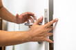 © Chanakon - Hand clamped door. A young man shut the door of the house so carelessly and clumsily that the door grabbed his hand finger pinched.