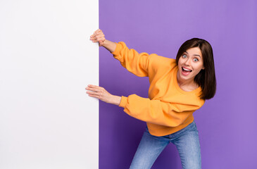 Wall Mural - Photo of pretty cute optimistic lady wear orange stylish sweater hand hold empty space card poster isolated on purple color background