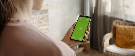 GREEN SCREEN CHROMA KEY Caucasian female using a phone inside her apartment. Vertical orientation