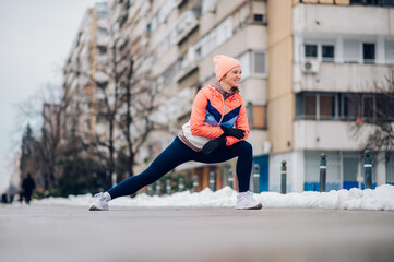 Wall Mural - Woman does stretching before training in the snow in the winter.