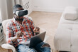 Modern african american man wearing vr glasses working at laptop, interacting with virtual reality