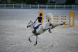 White sport horse in a show jumping competition kicks and bucking. Strong grey horse kicking and bolting. Sports horse and rider at the tournament.