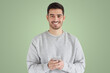 © Damir Khabirov - Young handsome man holding smartphone looking at camera with smile standing on green background