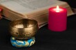 Closeup of Tibetan bell with an old spiritual book and red candle