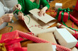 © master1305 - Cropped image of people decorating gifts, covering present boxes with wrapping paper and ribbons. Joyful holiday preparation