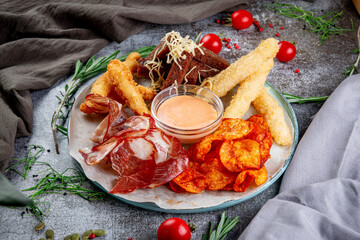 Wall Mural - An assortment of beer snacks. Fried potato chips, cheese and chicken nuggets, dried bacon slices, gravy and croutons