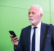 © Solid photos - Senior businessman talking on the smart phone in front of corporate office building