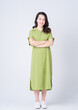© Timeimage - Full length image of young Asian woman wearing green dress on background
