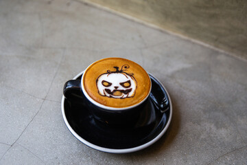 Sticker - Black cup of cappuccino coffee with latte art of halloween symbol pumpkin from cinnamon on milk foam