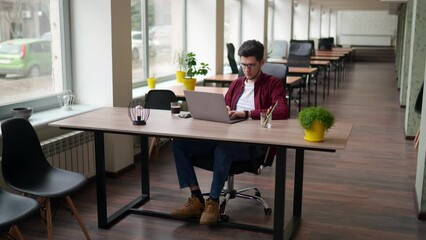 Wall Mural - young freelancer man working with laptop at bright spacious coworking alone. stylish creative design