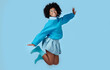 © Nicholas Felix/peopleimages.com - Blue, jump and happy black woman in a studio with trendy, cool and stylish clothes with a background. Happiness, smile and portrait of a young african model with energy, excited and joy.