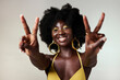 © N Felix/peopleimages.com - Black woman, peace sign and fashion afro hairstyle on studio background with style, trend and makeup cosmetics. Portrait, fun or happy beauty model with playful and good energy hands gesture in Congo