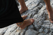 cropped view of barefoot woman with ankle bracelet and man standing on rocks.