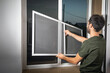 © andranik123 - Man installing the mosquito net on the window.