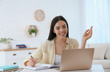 Sticker - Young woman taking notes during online webinar at table indoors