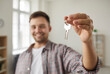 © Studio Romantic - Happy owner holding and showing the key to his new home. Close up of house keys in the hand of a young man. Real estate background. Concept of buying property. Soft focus