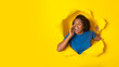 Black Female Shouting Through Hole In Torn Yellow Paper Background