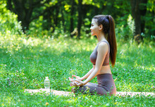 Beautiful Asian Woman Practicing Yoga, Sitting In A Lotus Pose At The Meadow.