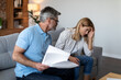 Despaired sad mature caucasian couple work with documents, pay bills, taxes have stress in living room