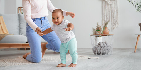 Poster - African-American mother teaching her little baby to walk at home