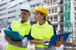 © JackF - Two engineers working on a construction site are holding a laptop and an estimate in their hands, discussing a construction ..plan