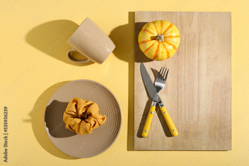 Autumn table setting with pumpkin on yellow background