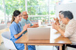 © narong - Asian senior man and woman enjoy to talk and fun with activity of nurse or doctor during teach with laptop on table in living room of clinic or hospital.