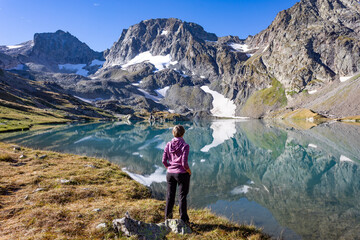 Wall Mural - The girl stands against the backdrop of mountain peaks and a blue lake. Beautiful mountain landscape for vacation, travel and healthy lifestyle