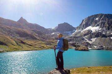 Wall Mural - The girl stands against the backdrop of mountain peaks and a blue lake. Beautiful mountain landscape for vacation, travel and healthy lifestyle