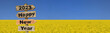 2023 happy new year written on a direction sign in front of field of yellow colza rapeseed blooming under blue sky  colors of ukrainian flag