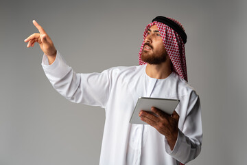 Wall Mural - Arab businessman using digital tablet on gray background