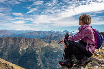 Wall Mural - The girl is sitting on the pass against the backdrop of mountain peaks. Beautiful mountain landscape for recreation, travel and a healthy lifestyle. On the back plan is the summit of Elbrus. Caucasus,