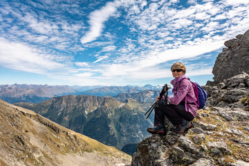 Wall Mural - The girl is sitting on the pass against the backdrop of mountain peaks. Beautiful mountain landscape for recreation, travel and a healthy lifestyle. On the back plan is the summit of Elbrus. Caucasus,