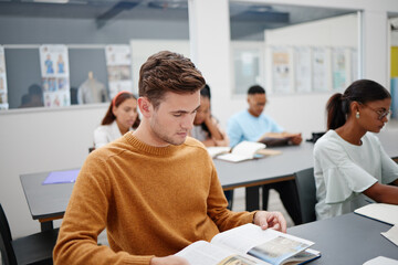 Poster - Education, university student and man reading book in classroom, studying or assignment research. Learning, college and person with textbook, exam or test preparation and knowledge search at desk.