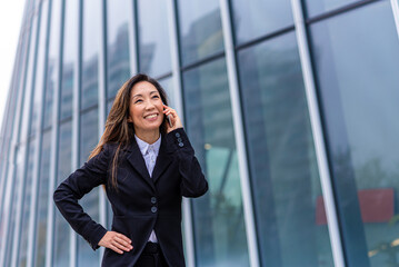 Japanese mature woman using smart phone, business person rejoices at the successes achieved, concept of equality and gender equality in the world of work and finance