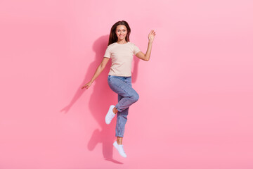 Canvas Print - Full length photo of cute friendly girl dressed beige t-shirt jumping high waving hi arm isolated pink color background