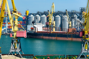 Wall Mural - industrial seaport infrastructure, sea, cranes and dry cargo ship, grain silo, bulk carrier vessel and grain storage elevators, concept of sea cargo transportation