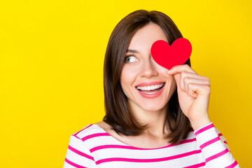 Wall Mural - Photo of nice cute gorgeous woman with bob hairdo striped shirt look empty space hold heart close eye isolated on yellow color background