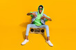 Full length photo of excited funky person sitting vintage boom box have fun isolated on yellow color background