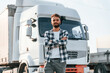 © standret - With arms crossed. Young truck driver is with his vehicle at daytime