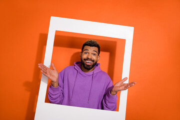 Wall Mural - Portrait of cheerful person raise opened arms through paper album card isolated on orange color background